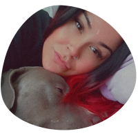 A picture of our groomer Caitlin and she is holding her grey pitbull dog