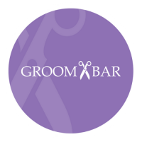 The Groombar logo in a purple circle with faded out scissors in the background